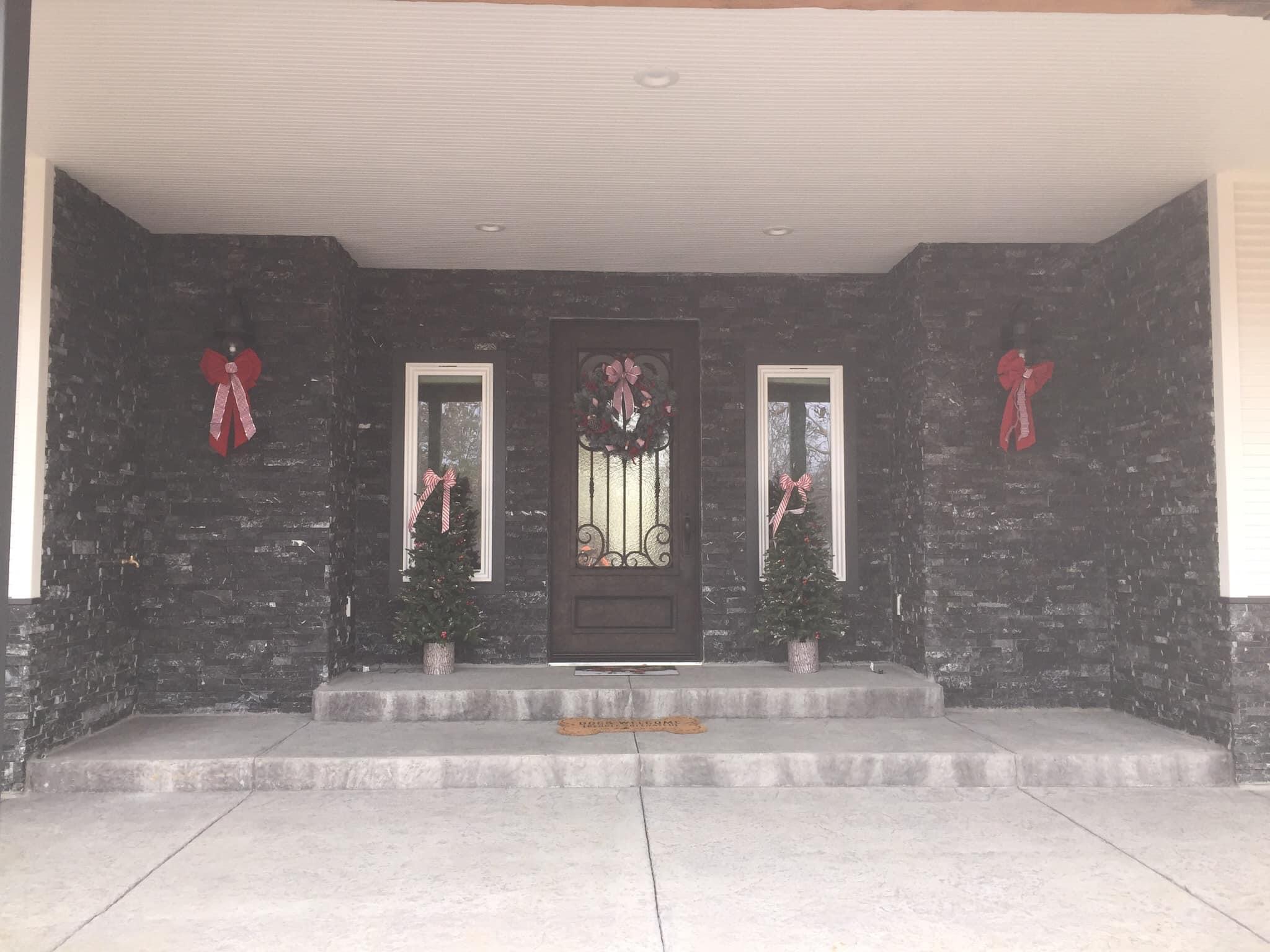 Dark stacked natural stone around a covered front entry