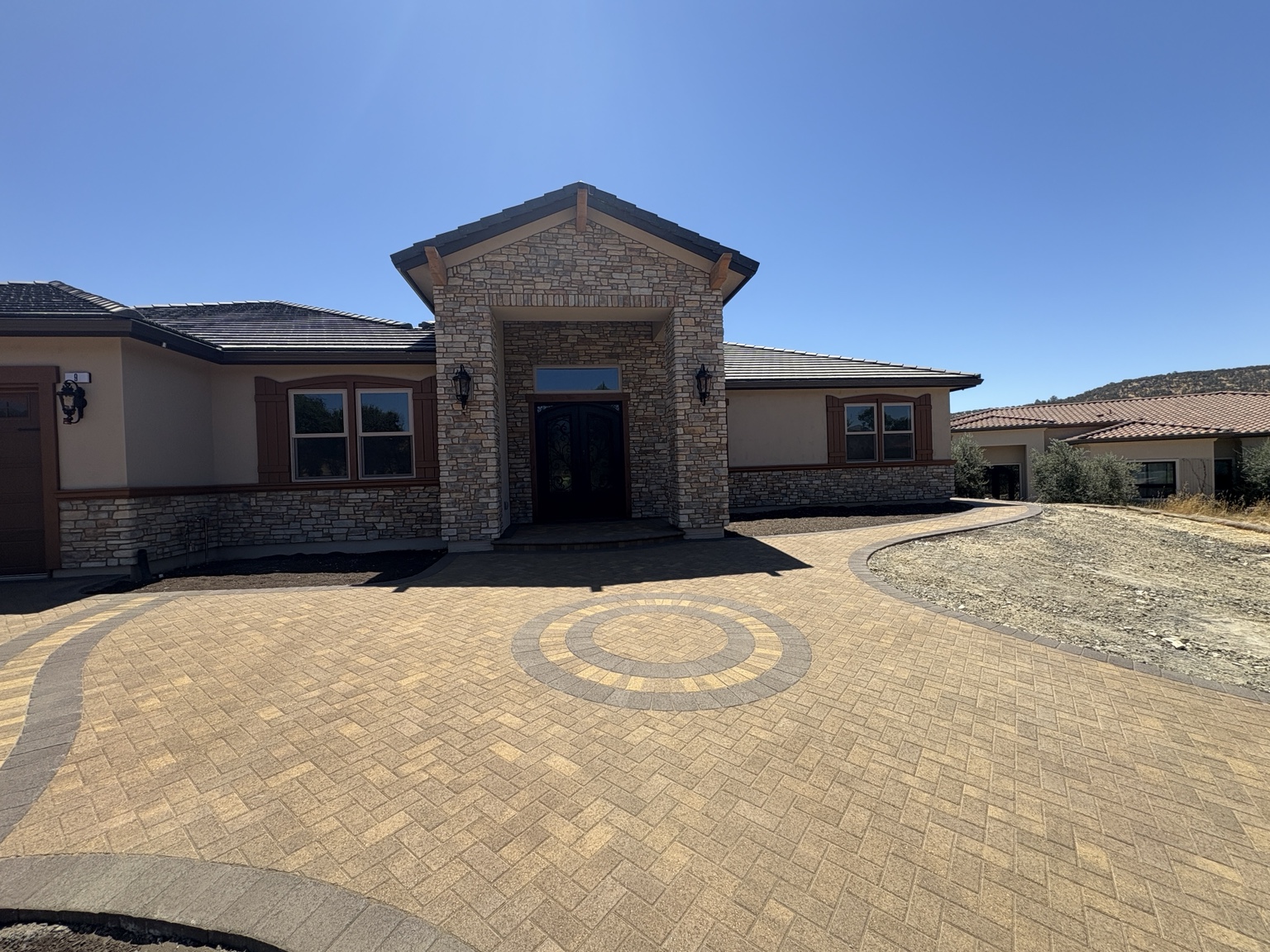 Stone veneer on a home exterior and entry beside a paver driveway