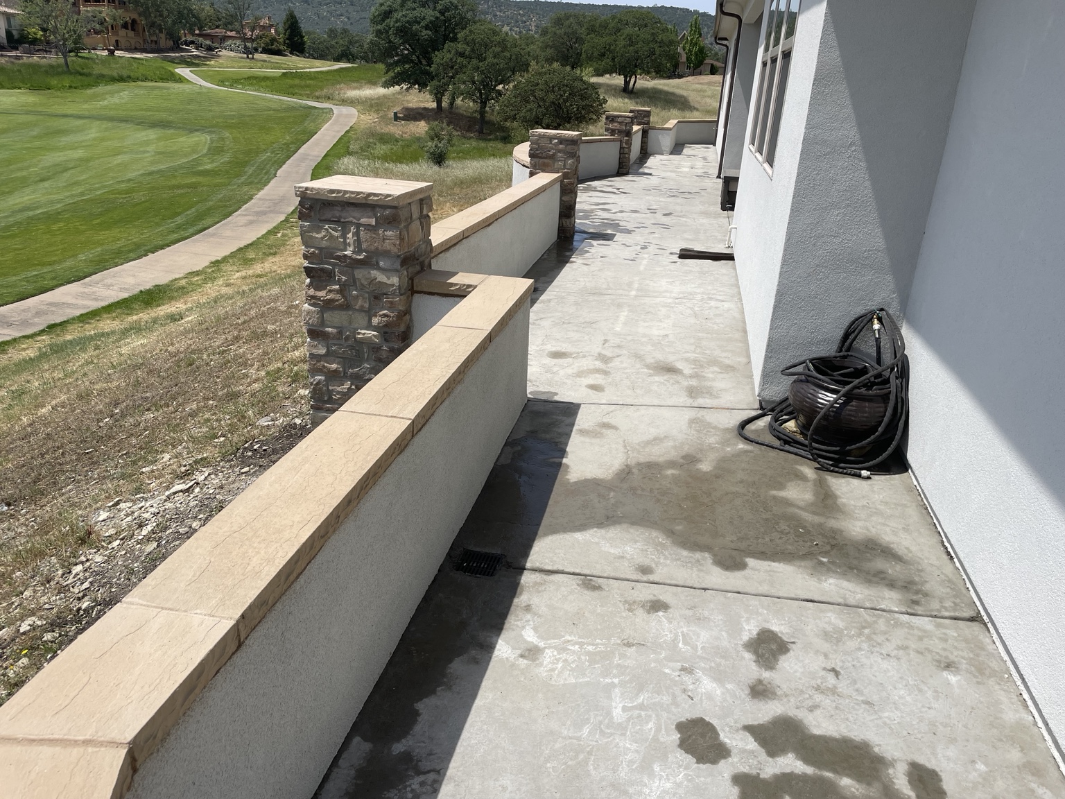 Low masonry wall with capstones and stone-clad columns beside a house